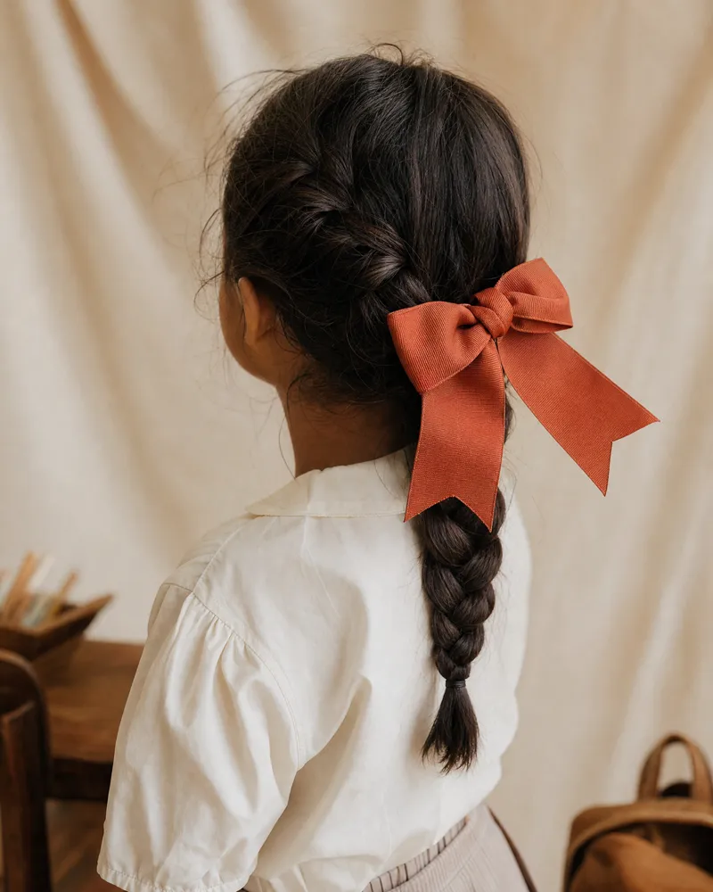 Menina com laço no cabelo, pronta para a escola